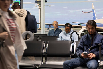 Busy airport terminal filled with people traveling by plane, scrolling on smartphones. Diverse...