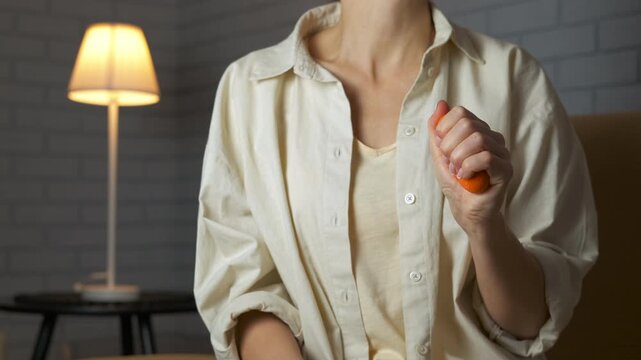 Woman compressing hand expander for wrist rehabilitation. Young woman's hand squeezing a rubber ring expander for exercise, strengthening her grip and forearm muscles in a calm home setting