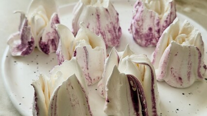 Handmade marshmallows shaped like tulips with berry patterns, a gourmet dessert served on a ceramic...
