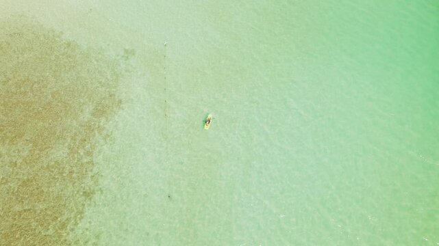Person kayaking over crystal clear shallow water at Bacalar lagoon in Mexico