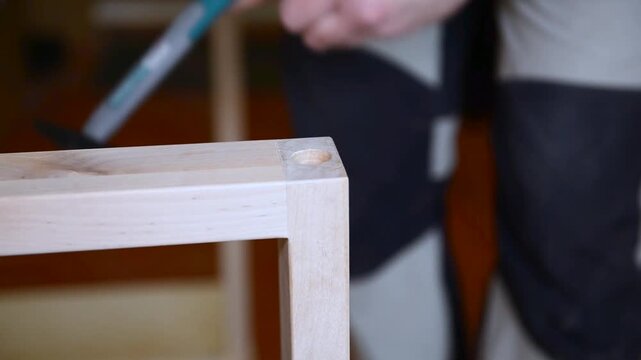 A man with works in his workshop. Close up of male hands installing a mortise nut for furniture legs legs. Profession carpenter. A man works with a tree.