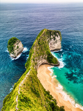 Aerial view of Kelingking Beach featuring the iconic T-Rex shaped cliff, turquoise ocean waves, and white sand Nusa Penida, Bali, Indonesia.