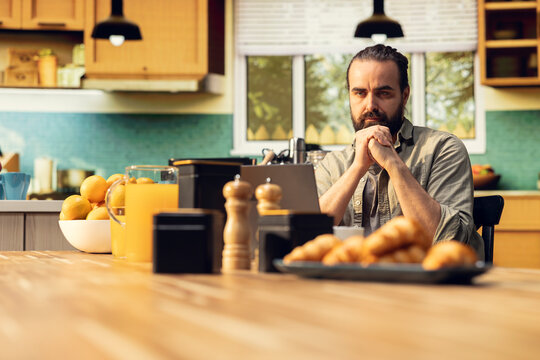 Focused freelancer does nervous tic and cracking knuckles at laptop, working remotely in the kitchen with involuntary movements and nervous habit. Popping sounds from fingers.