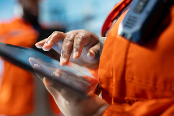 Close up of drilling rig specialist using tablet to evaluate spill prevention systems to reduce...