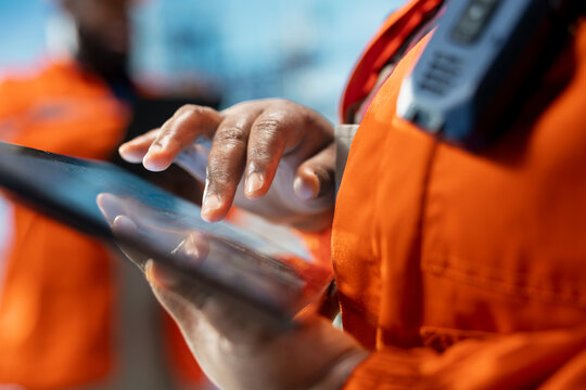 Close up of drilling rig specialist using tablet to evaluate spill prevention systems to reduce ocean contamination. Environmental protection professional monitoring carbon footprint with device