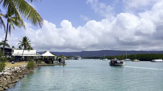 Waterfront view of Port Douglas with boats on Packers Creek in tropical North Queensland, Australia. Scenic marina setting with calm water and coastal town atmosphere.