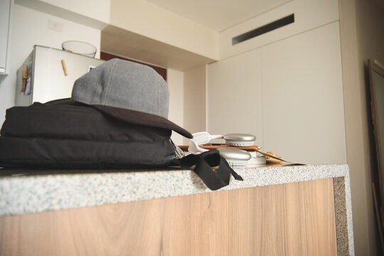 Backpack, hat, and headphones resting on a kitchen counter in a modern apartment