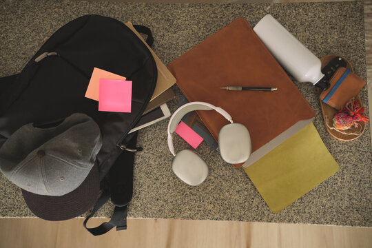 Student essentials including a backpack, headphones, and notebooks on a granite desk, conveying a study area