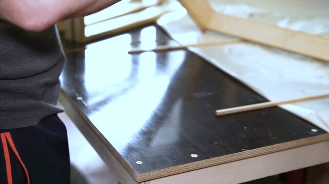 Professional cabinet maker sanding a wooden board with a hands to achieve a smooth surface before applying varnish or oil. Woodworking and craftsmanship concept