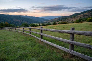 Fototapeta premium Scenic mountain landscape with wooden fence at sunset