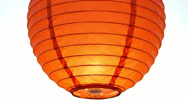 Close-up of a richly colored red orange paper lantern hanging against a stark white background