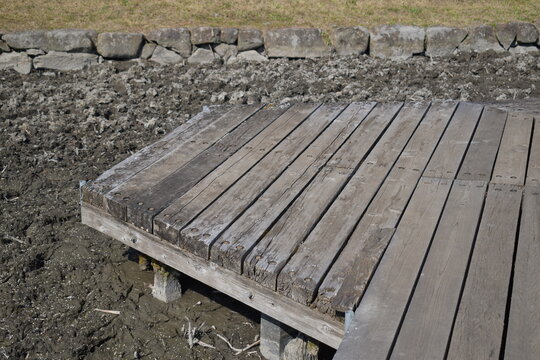 Rustic wooden deck over a dry muddy field.