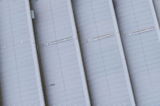 Aerial view of the modern corrugated metal roof with repeating ribbed patterns and industrial textures in Leccio, Toscana, Italy.