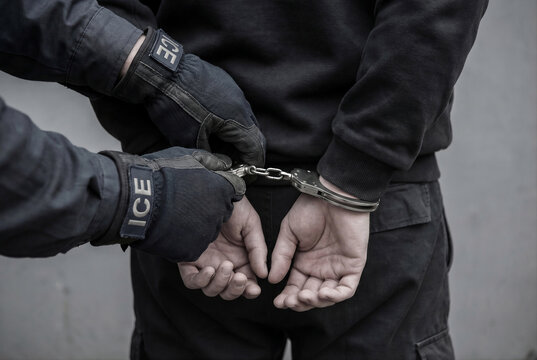 ICE federal agents arresting citizen and applying handcuffs to suspect on city street for news report