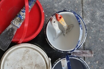Overhead view of open paint buckets with used brushes inside © ahmadiliandy