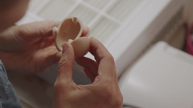 Closeup of artist opening silicone doll head showing detailed craftsmanship, inspection process and careful handling in workshop