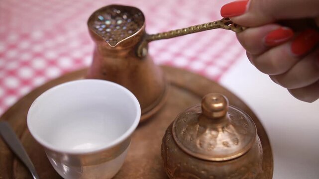 4k video of traditional Turkish coffee served in copper ware being poured into a cup. 
