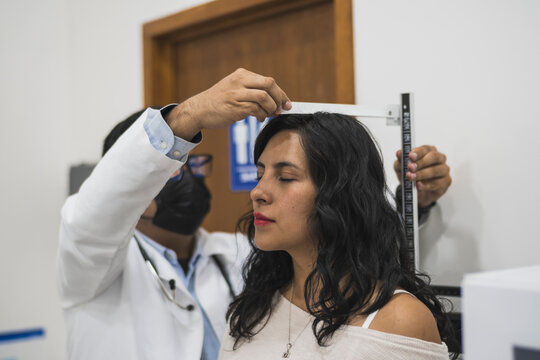 Doctor measuring a female patient's height on a scale
