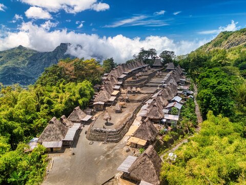 Aerial view of Bena Traditional Village with its iconic thatched roof houses and stone terraces nestled among lush green mountains in Kecamatan Jerebuu, Nusa Tenggara Timur, Indonesia.
