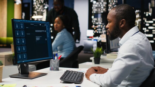 Male PC user interacting with AI chat system on computer at office after hours, highlighting the evolution of artificial intelligence. Chatbot services and digital tools for productivity.