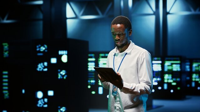IT programmer in server hub using tablet to find firewall misconfigurations affecting mainframes performance and connectivity, leading to slow data transfer rates and poor client communication