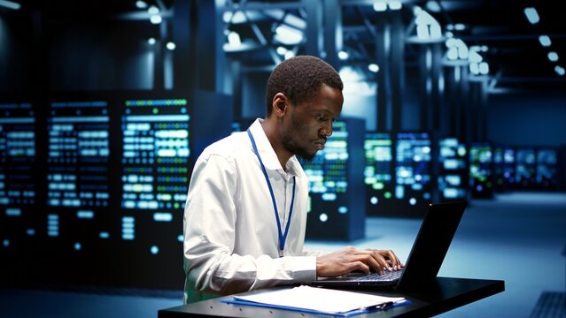 Computer scientist fixing server operational issues arising due to high CPU usage, insufficient memory and low disk space. African american expert monitoring performance trends