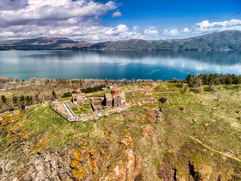 Aerial view of Sevanavank monastery on a rocky hill overlooking the blue waters of Lake Sevan under a cloudy sky, Sevan, Gegharkunik Province, Armenia.