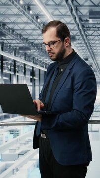 Vertical video Portrait of cheerful man looking at data on laptop, improving microchips fabrication supply chain yield. Jolly manager visualizing semiconductors factory production line bottlenecks