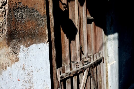 The an old wooden fence with a worn color and distinctive texture in front of the main entrance of a house in the countryside.