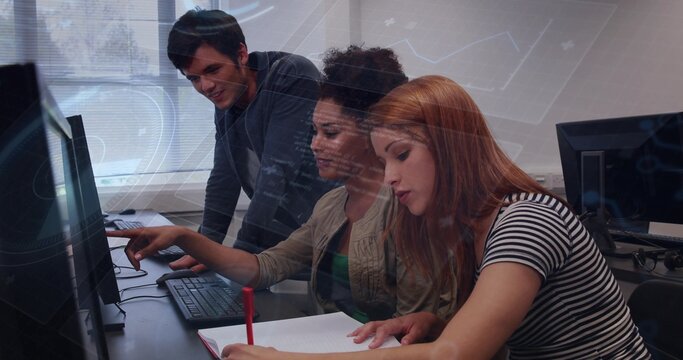 Pointing group of three students collaborating at computer lab, writing with red pen