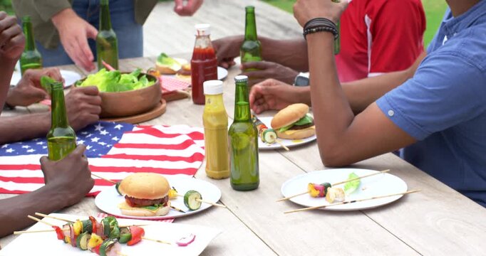 Vertical video: Diverse male friends reaching salad grabbing beer passing ketchup at deck barbecue