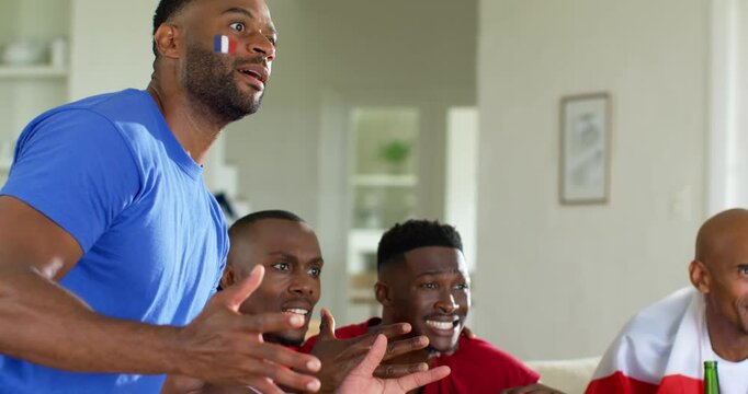 Diverse male friends watching soccer match on TV, reacting to goal, cheering, slumping with beer