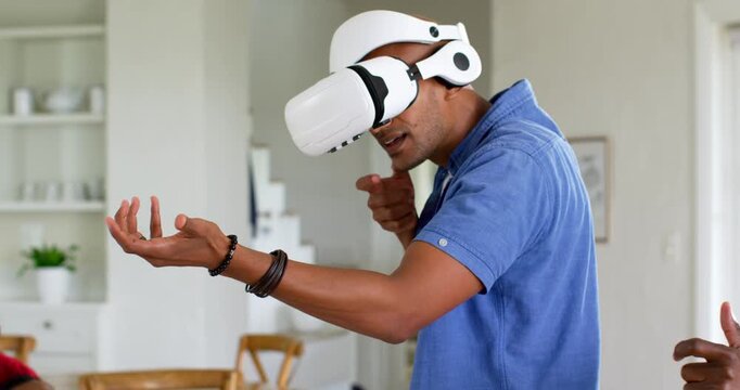 Vertical video: African American man in VR headset making gestures after game with friends at home