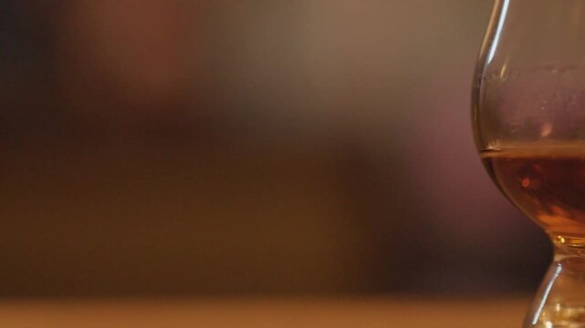 Glencairn whiskey glasses filled with golden amber spirit on wooden table with cinematic panning motion.