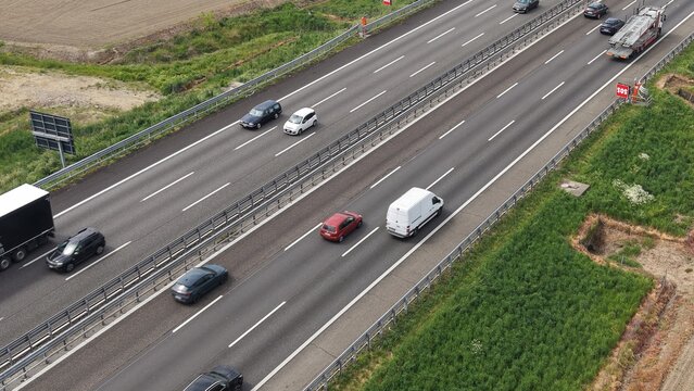 Highway Traffic Flow: A panoramic aerial view captures the steady flow of vehicles on a multi-lane highway, surrounded by green fields and under an expansive sky.