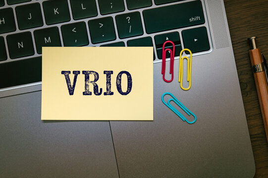 Eye-catching image of VRIO text on sticky note. The word stands for Value, Rarity, Inimitability, Organization. Shown with laptop, clips.