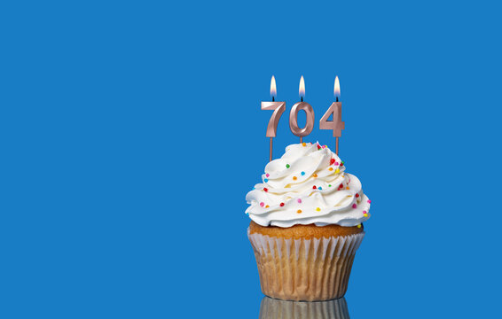 Birthday Or Anniversary Cupcake With Lit Candles; Candles Forming The Number 704