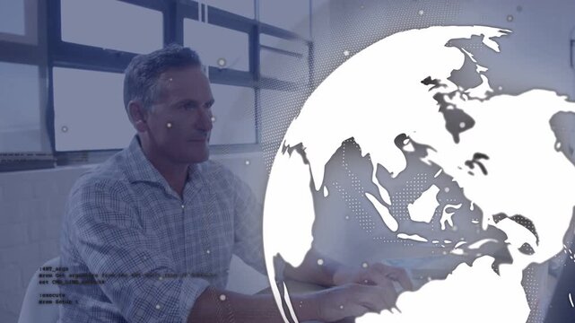 Typing mature man wearing printed shirt using mouse at computer in bright office with globe overlay