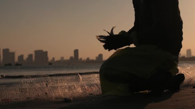 Asian Seafood Sorter Cleaning Catch On Da Nang Shoreline Sunrise Kneeling In Wet Sand Hands Handling Small Fish And Shells Net Skyline Backdrop Warm Amber Tones Quiet Early Market Mood