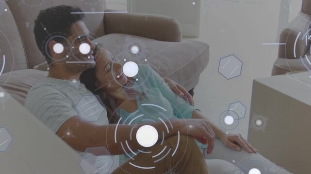 Leaning couple cuddling on floor in living room after packing boxes, HUD overlays visible