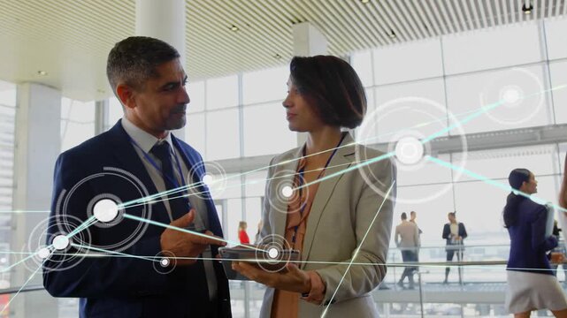 Woman tapping tablet and man pointing in atrium, network nodes expanding across frame for business