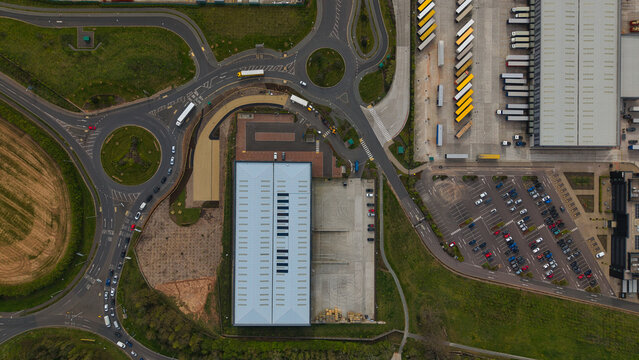 Aerial view of Appleby Magna industrial park featuring a large warehouse, parking lots with cars, and trucks at loading docks in Appleby Magna, England, United Kingdom.