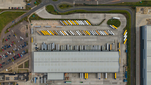 Aerial view of Appleby Magna industrial park featuring a large warehouse with rows of semi-truck trailers and loading docks in Appleby Magna, England, United Kingdom.