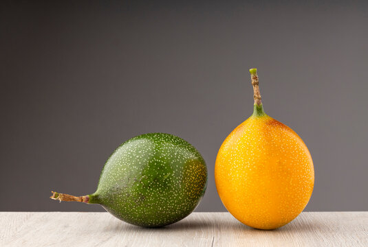Green and ripe Passiflora ligularis fruits in a minimalist studio composition.