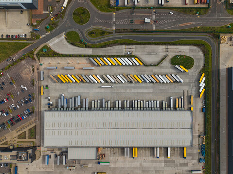 Aerial view of the Appleby Magna industrial park featuring a large warehouse with rows of parked semi-trailers and a nearby parking lot Appleby Magna, England, United Kingdom.