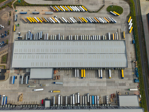Aerial view of Appleby Magna Industrial Park showing a large logistics warehouse with rows of parked trucks and trailers in Appleby Magna, England, United Kingdom.