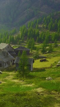 In the mountains, buildings sit in a green field surrounded by trees. The scene shows farm animals grazing under the sun. It is daytime in a rural area.