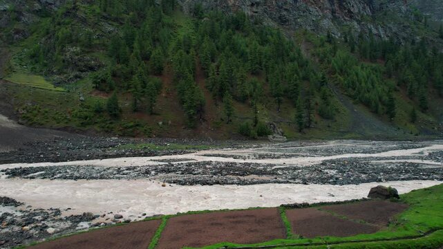 4K beautiful Aerial landscape with flowing Chenab river in Lahaul, Himachal Pradesh, India. Green forest trees, farms and river flowing in valley during summer season. Travel and holidays concept.