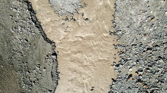 Aerial view of natural river stream during summer season at Miyar valley, Lahaul, India. Top down view of muddy mountain river flowing through rocky terrain. Nature background.