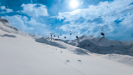 Ski lift over pristine snowy mountains with blue sky and clouds in Andes winter travel destination.